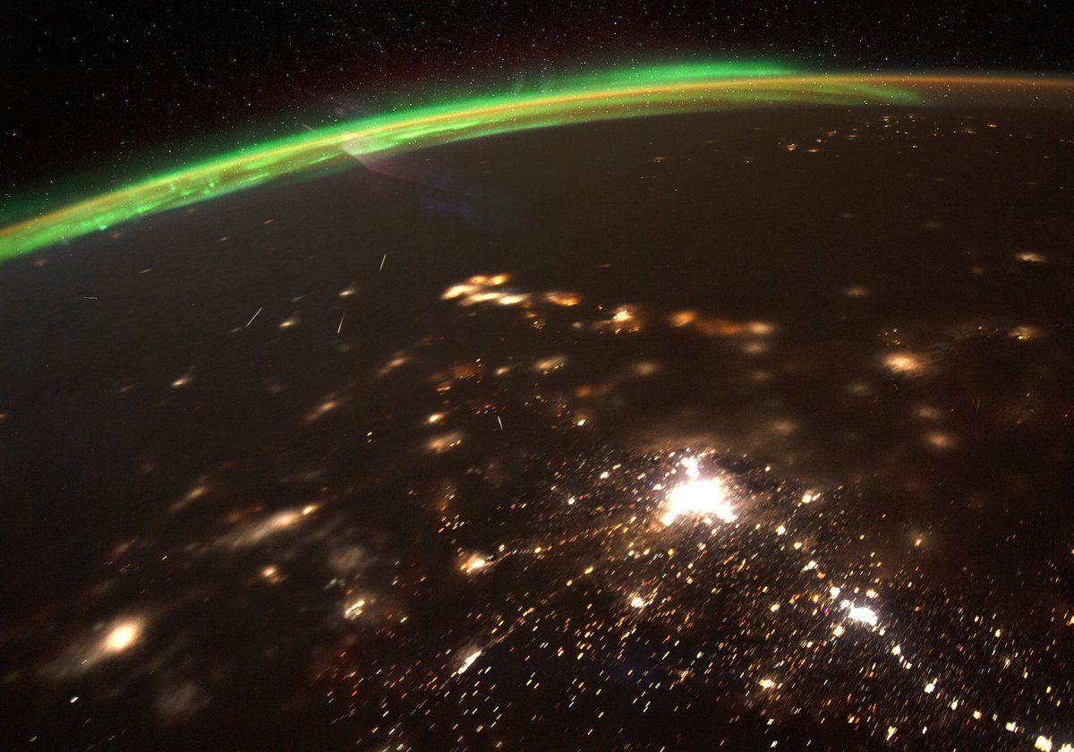 Meteors streaking over a nighttime Earth with city lights seen from space.