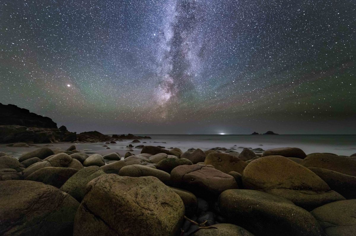 Astrophotography for beginners: Image of night sky with rocky beach in foreground