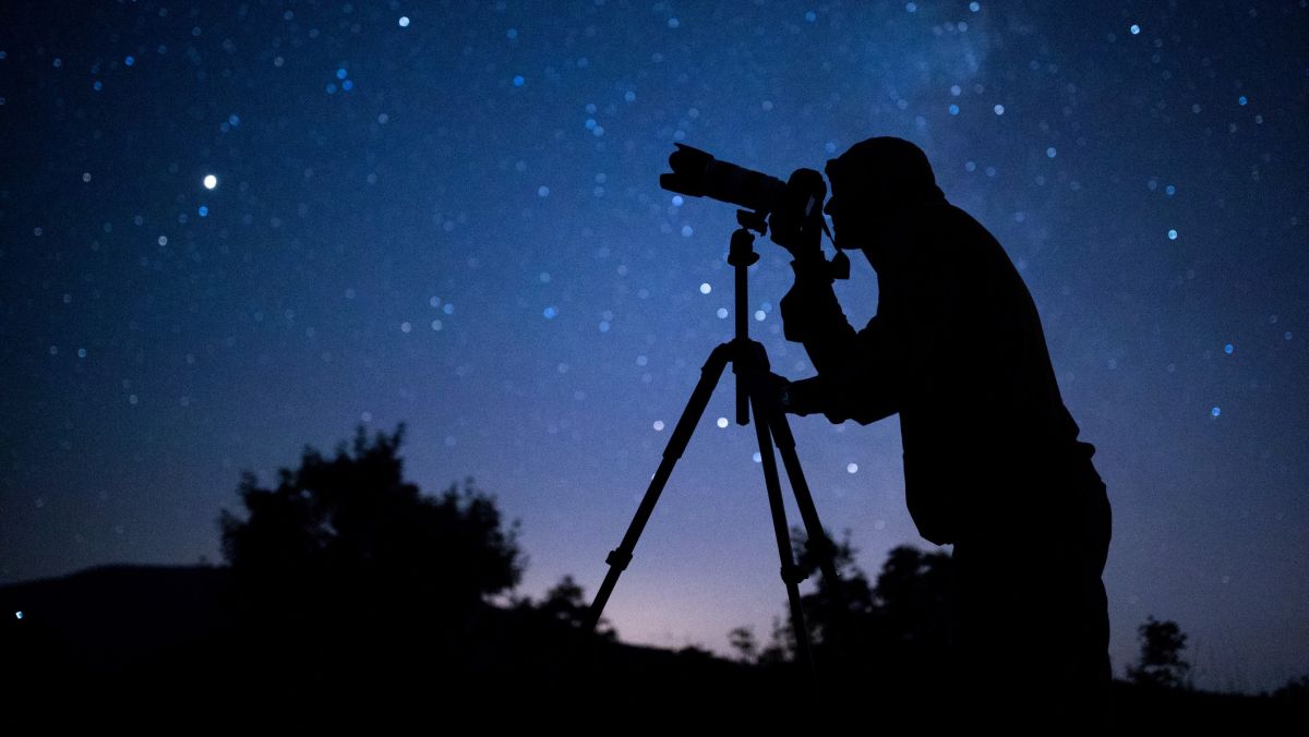 Astrophotographer observing the night sky filled with stars.