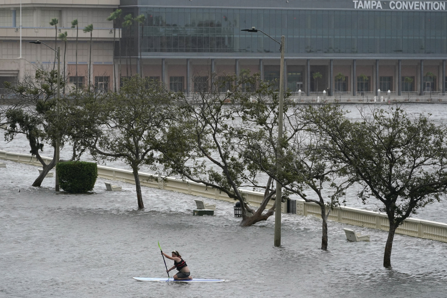 Zeke Pierce rides his paddle board down the middle of a flooded Bayshore Blvd in downtown in Tampa, Fla., Wednesday, Aug. 30, 2023.  Hurricane Idalia steamed toward Florida